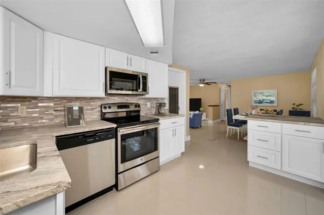 a kitchen with granite countertop white cabinets and stainless steel appliances