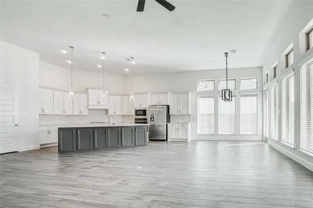 a large kitchen with stainless steel appliances granite countertop a stove a sink and white cabinets