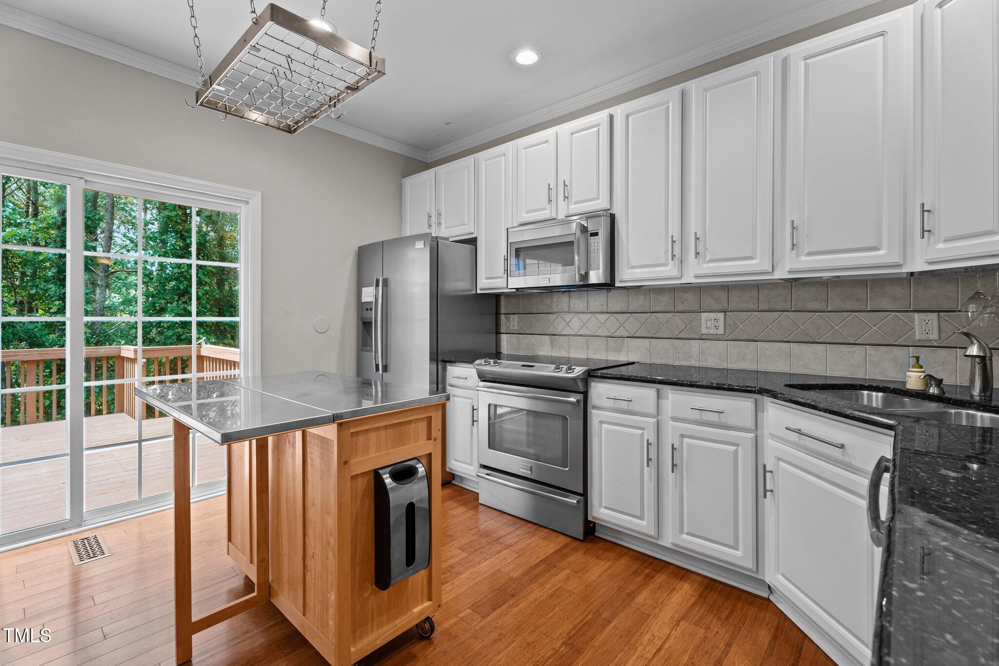 5310 Echo Ridge Road Raleigh, NC 27612 - Photo 8 of 29 a kitchen with stainless steel appliances granite countertop a stove a refrigerator and white cabinets with wooden floor