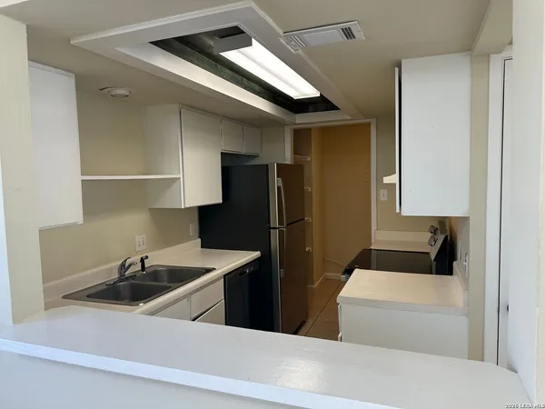 a kitchen with stainless steel appliances a sink a refrigerator and a cabinets