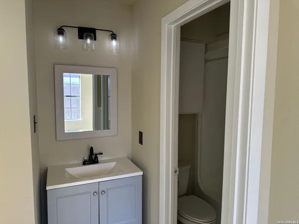 a bathroom with a toilet sink vanity and mirror