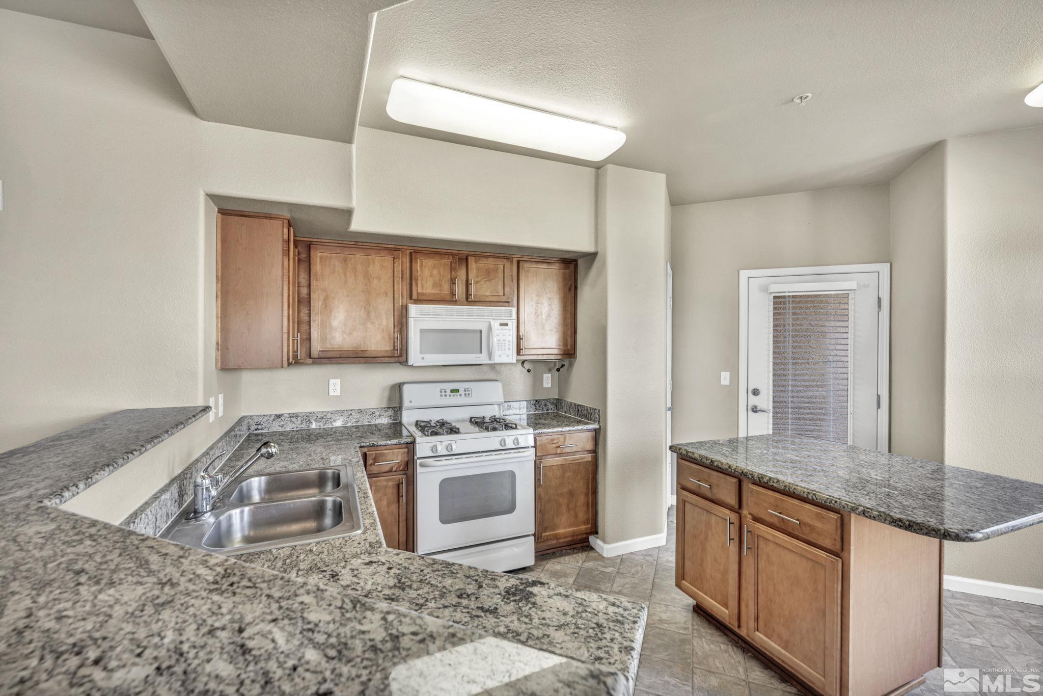 1325 South Meadows Parkway, Unit 412 Reno, NV 89521 - Photo 10 of 39 a kitchen with stainless steel appliances granite countertop a stove a sink and a granite counter tops