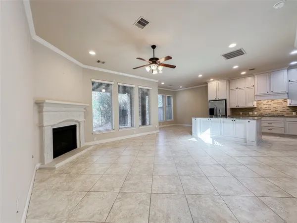 a view of an empty room with kitchen and fireplace