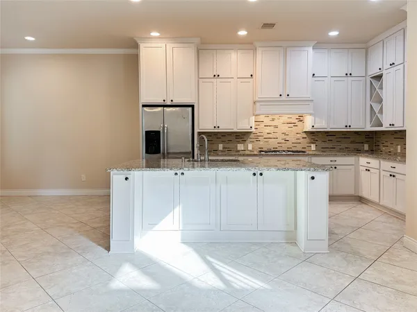 a kitchen with granite countertop a sink a stove a refrigerator and white cabinets