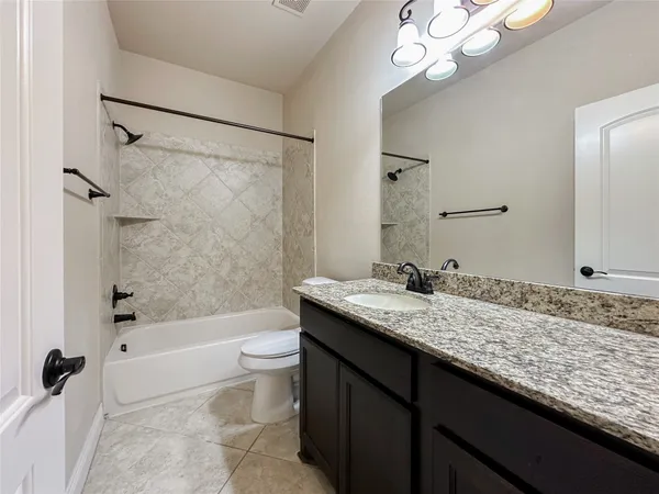 a bathroom with a granite countertop sink a toilet a mirror a bathtub and shower