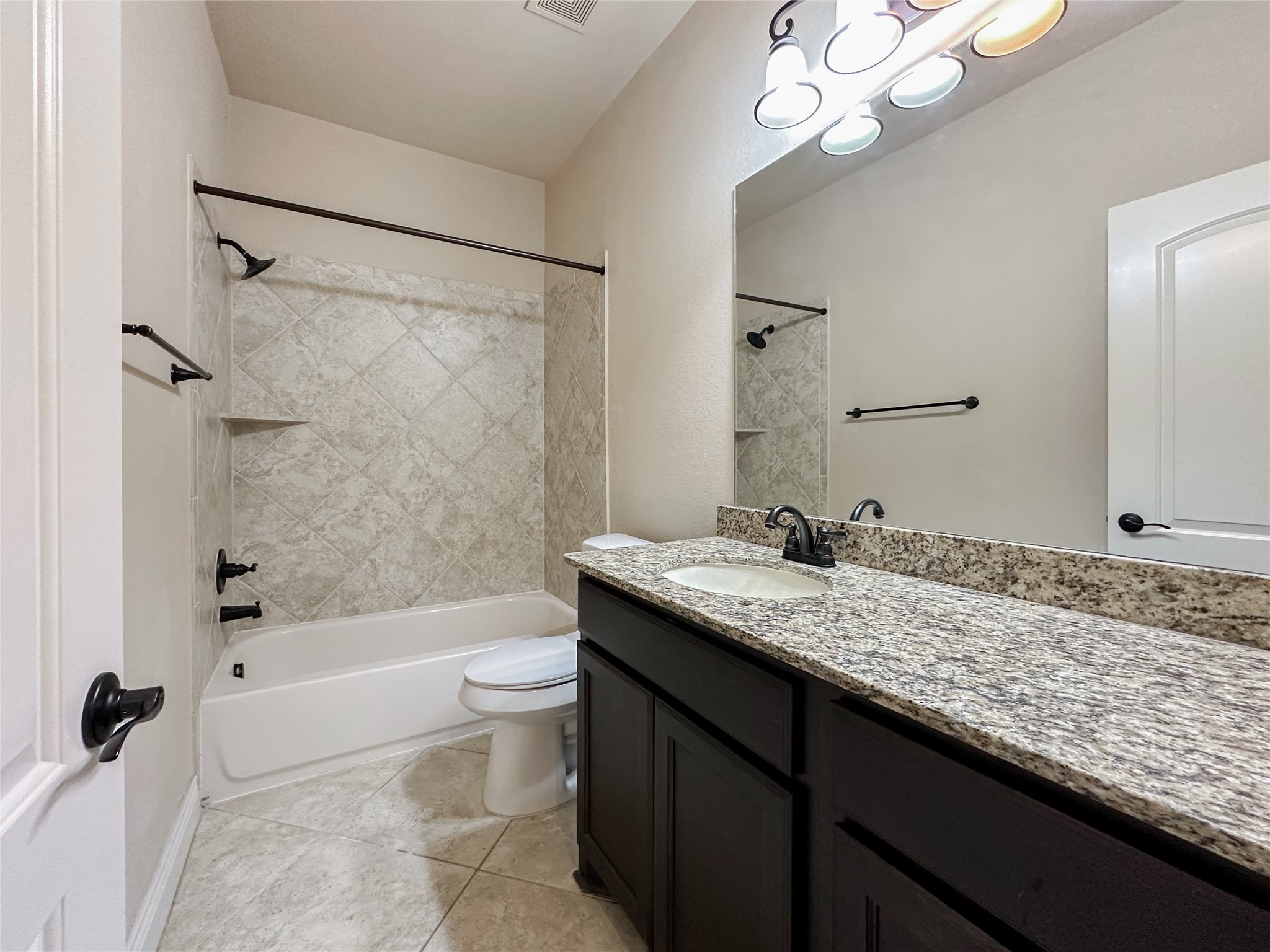 23 Jonquil Place Tomball, TX 77375 - Photo 38 of 50 a bathroom with a granite countertop sink a toilet a mirror a bathtub and shower