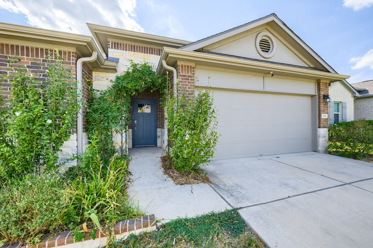 A classic brick facade and tidy concrete driveway frame this welcoming entry.