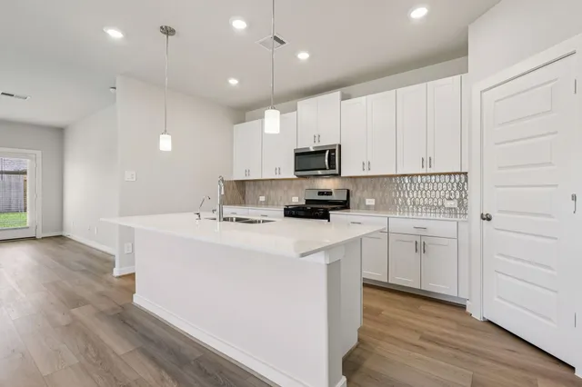 a kitchen with kitchen island a white counter top space cabinets and stainless steel appliances