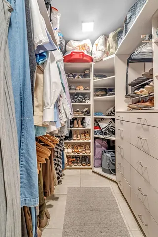 a view of walk in closet with clothes and shoes