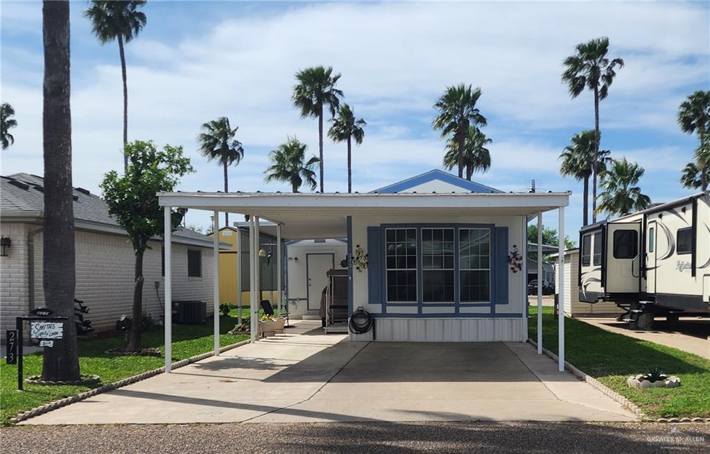 Manufactured / mobile home featuring a carport, central AC, and a front lawn