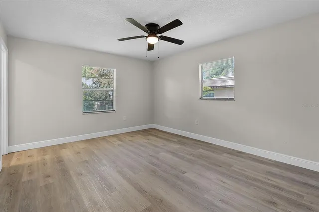 an empty room with wooden floor and ceiling fan