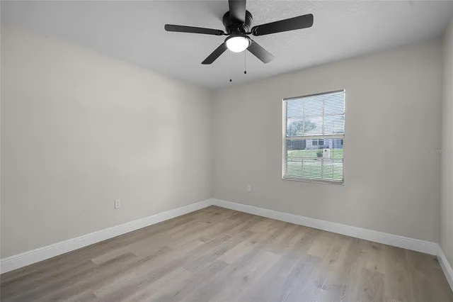 an empty room with a window and a fan