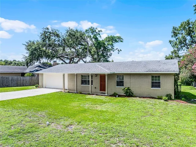 a front view of house with yard and trees in the background
