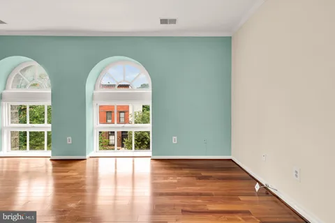 an empty room with wooden floor fireplace and windows