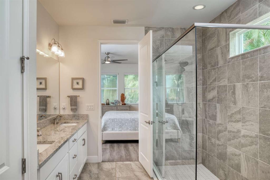 11539 Tapestry Lane Venice, FL 34293 - Photo 20 of 21 a en suite bathroom with a granite countertop sink mirror and shower
