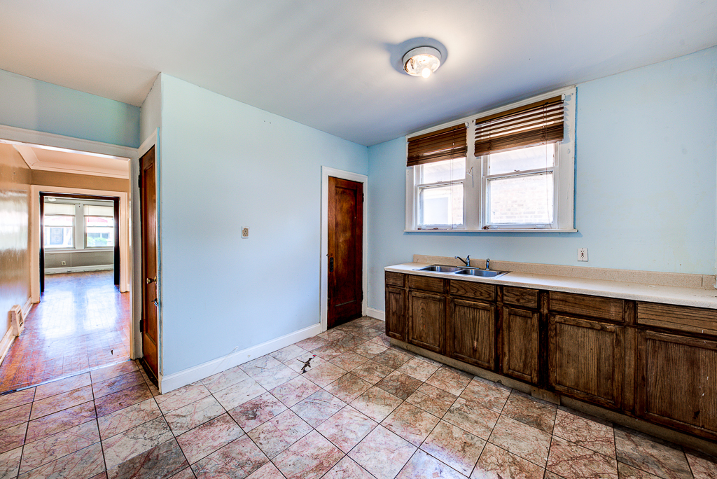 8024 South Perry Avenue Chicago, IL 60620 - Photo 8 of 37 a large kitchen with kitchen island granite countertop a refrigerator and a sink