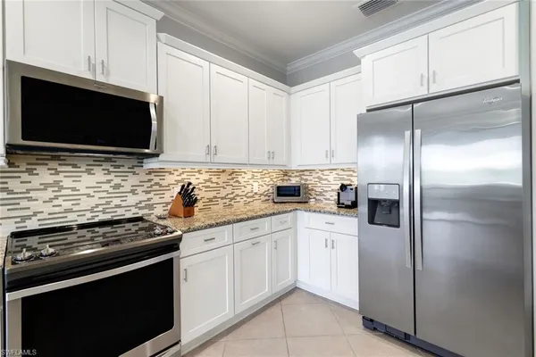 a kitchen with white cabinets and stainless steel appliances