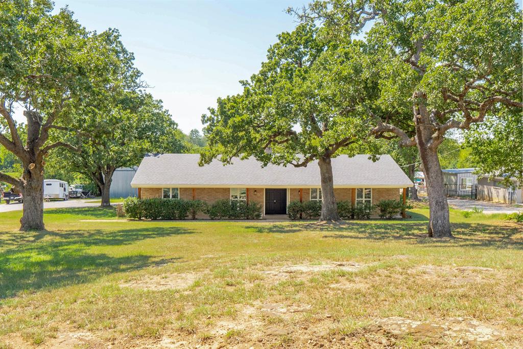 Ranch-style home featuring brick siding, a front yard, and roof with shingles
