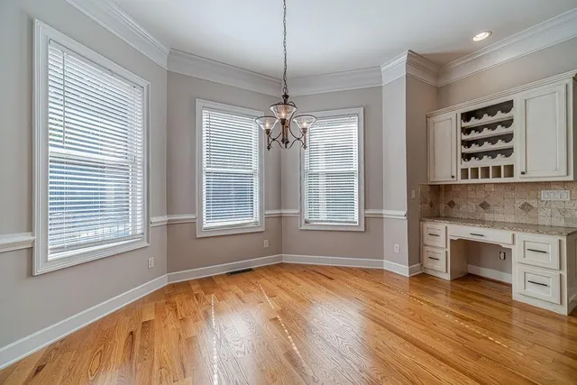 a kitchen with granite countertop a stove a sink and white cabinets with wooden floor next to windows