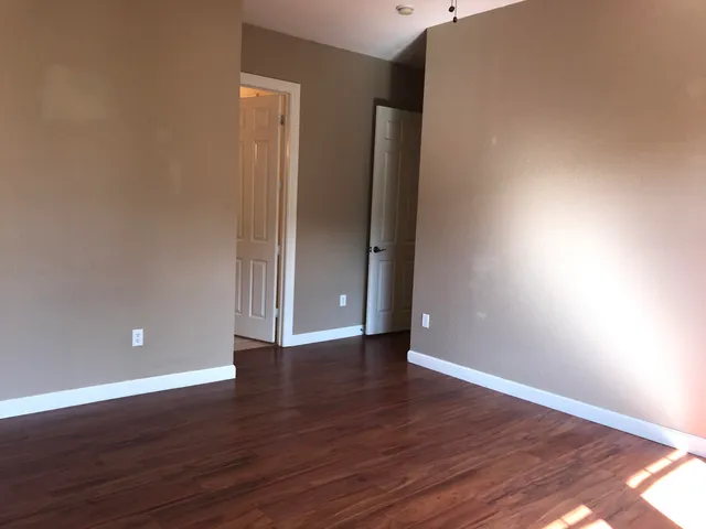 a view of room with hardwood floor and a ceiling fan