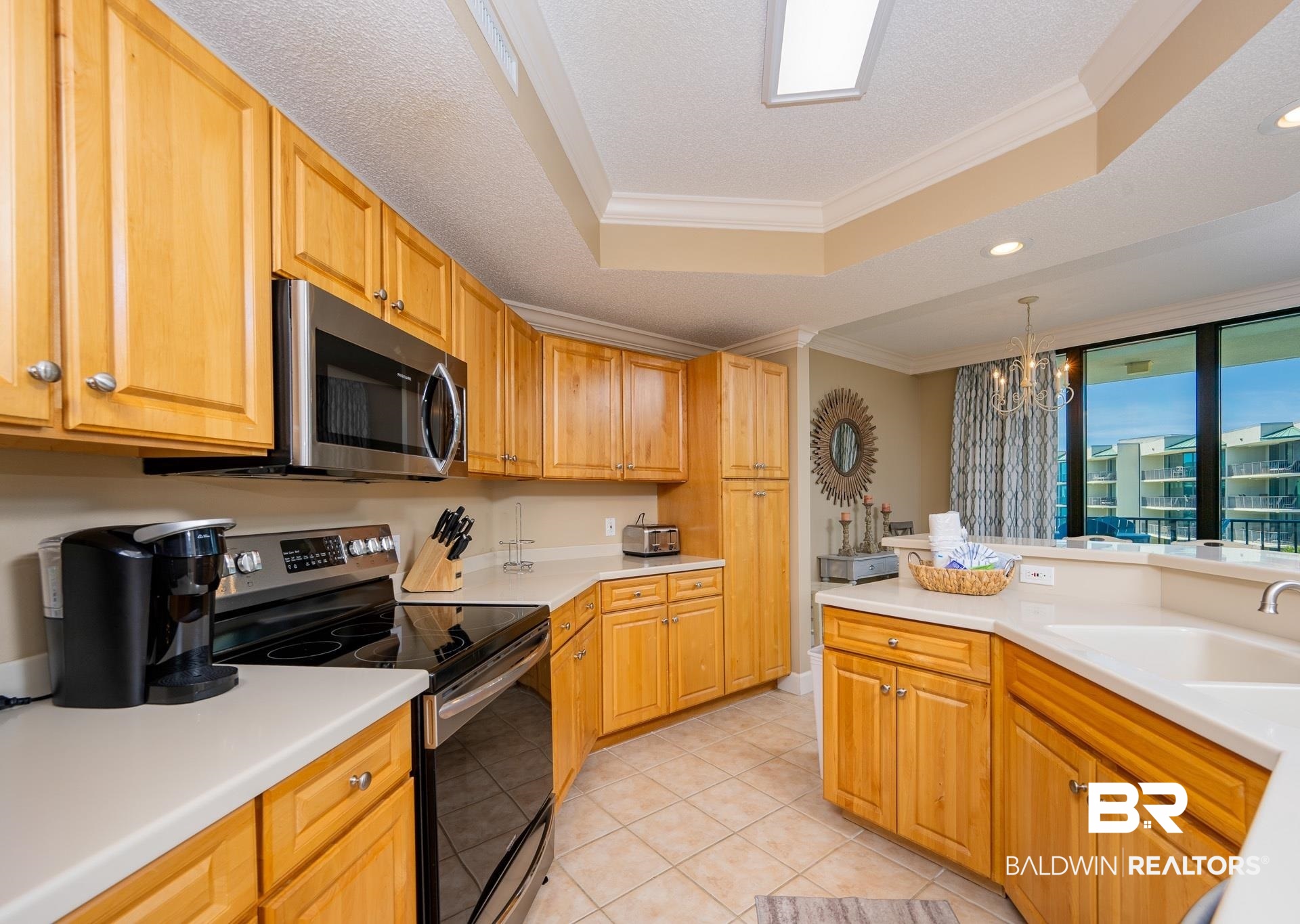 27580 Canal Road, Unit 1429 Orange Beach, AL 36561 - Photo 7 of 45 Kitchen with ornamental molding, stainless steel appliances, a chandelier, a raised ceiling, and light countertops