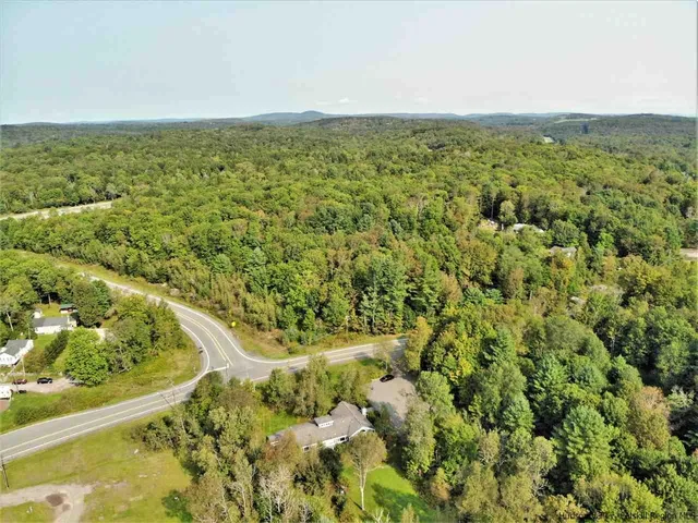 an aerial view of residential houses with outdoor space and trees