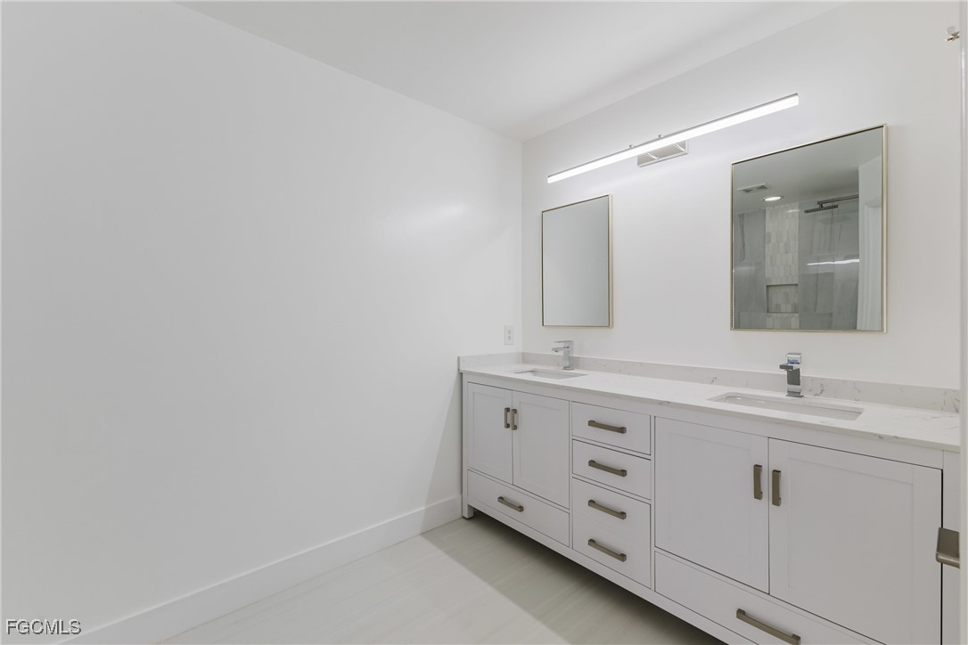 827 Hampton Circle, Unit 146 Naples, FL 34105 - Photo 20 of 36 a bathroom with a double vanity sink and mirror