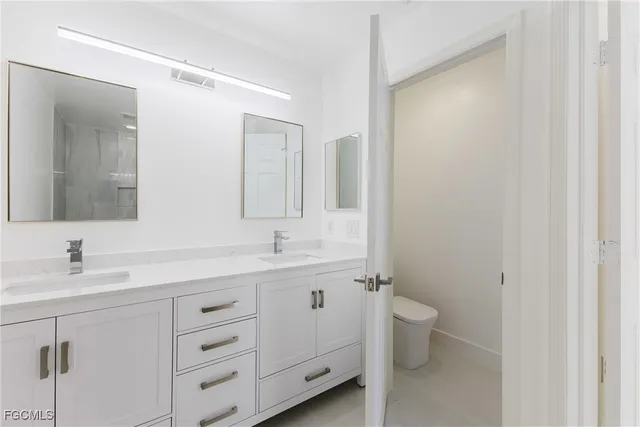 a bathroom with a double vanity sink toilet and mirror