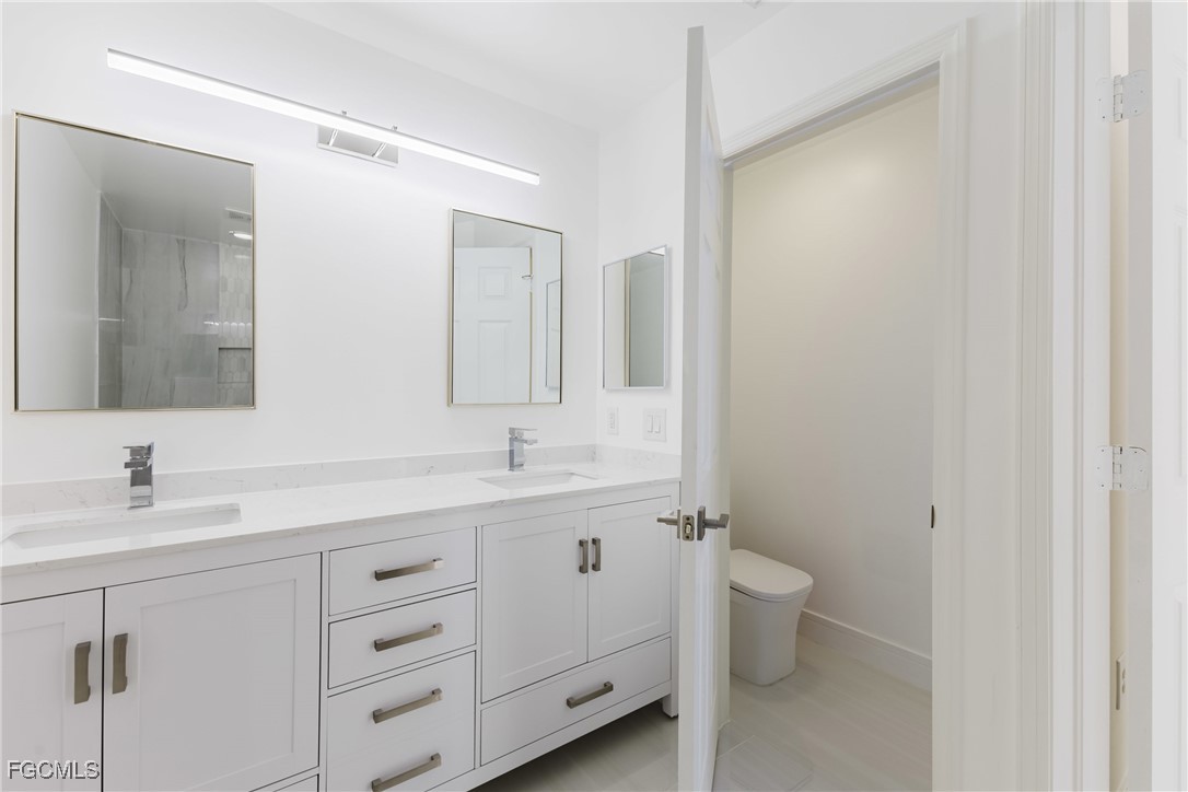 827 Hampton Circle, Unit 146 Naples, FL 34105 - Photo 22 of 36 a bathroom with a double vanity sink toilet and mirror