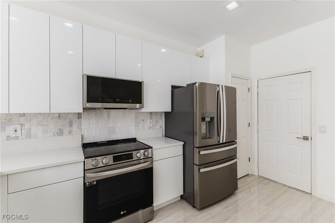 827 Hampton Circle, Unit 146 Naples, FL 34105 - Photo 6 of 36 a kitchen with stainless steel appliances a refrigerator a stove a microwave and cabinets