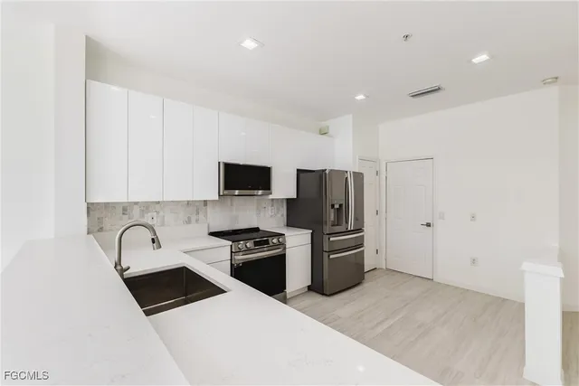 a kitchen with granite countertop a refrigerator stove and sink