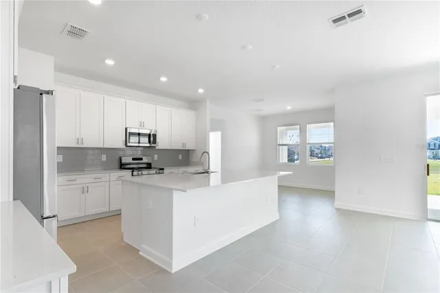 a kitchen with stainless steel appliances kitchen island granite countertop a refrigerator and a sink