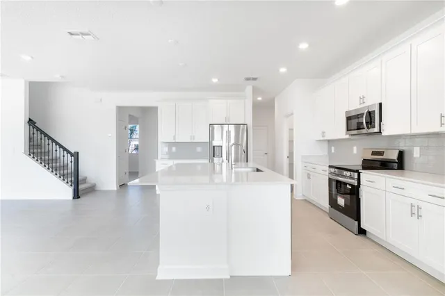 a kitchen with white cabinets appliances and a sink