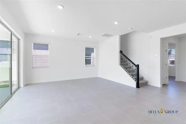 an empty room with staircase and windows
