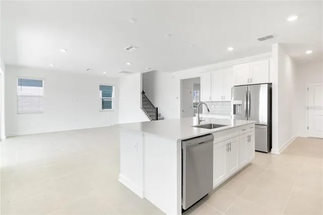 a view of a kitchen with refrigerator and white cabinets