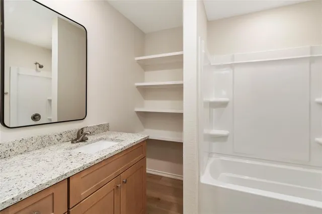 a bathroom with a granite countertop sink and a mirror a bathtub