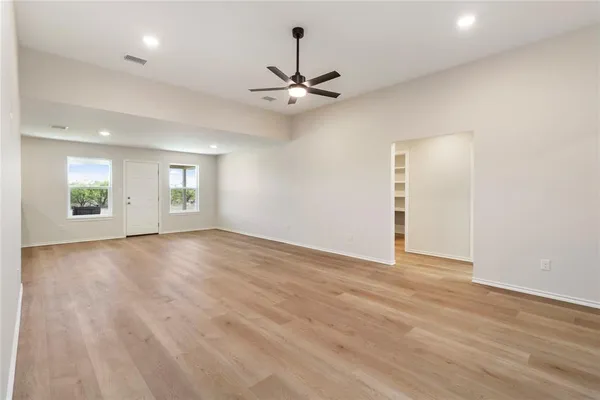 a view of an empty room with window and wooden floor