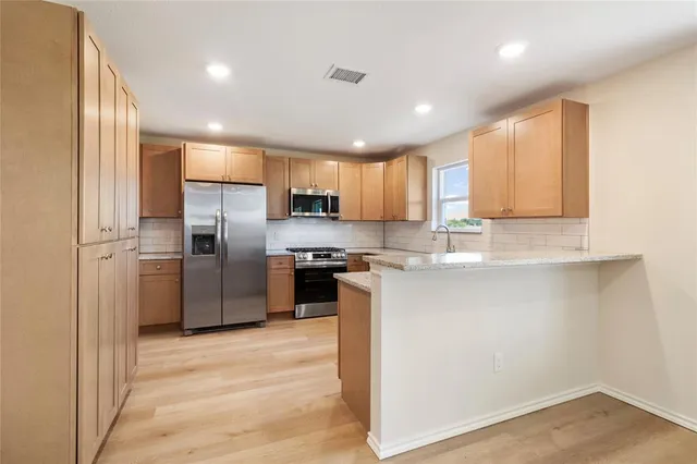 a kitchen with stainless steel appliances granite countertop a refrigerator a sink a stove and oven