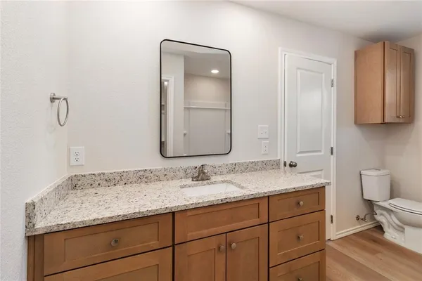 a bathroom with a granite countertop sink a toilet and a mirror