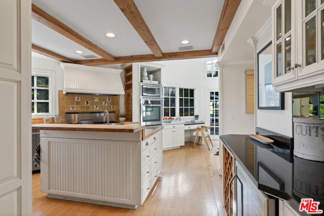 3371 Mandeville Canyon Road Los Angeles, CA 90049 - Photo 13 of 44 a open kitchen with stainless steel appliances granite countertop a stove top oven a sink a dining table and chairs with wooden floor