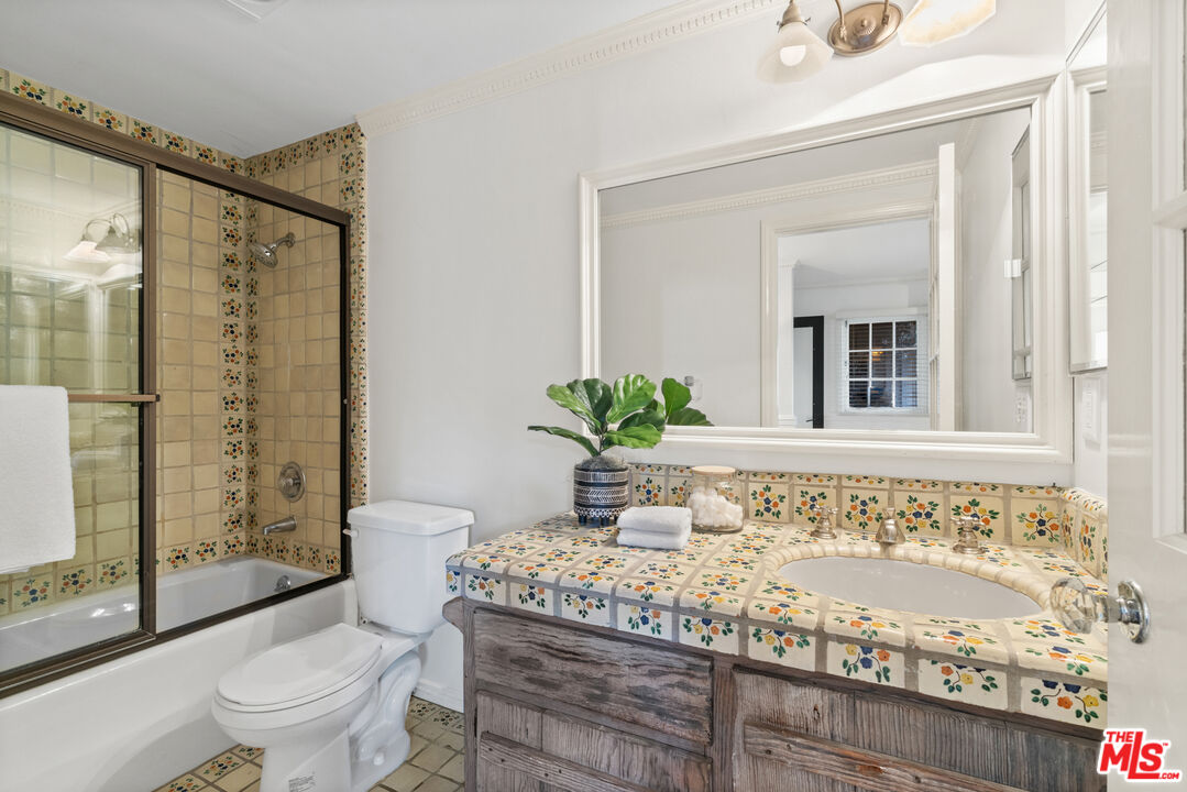 3371 Mandeville Canyon Road Los Angeles, CA 90049 - Photo 21 of 44 a bathroom with a granite countertop sink a toilet a mirror and shower
