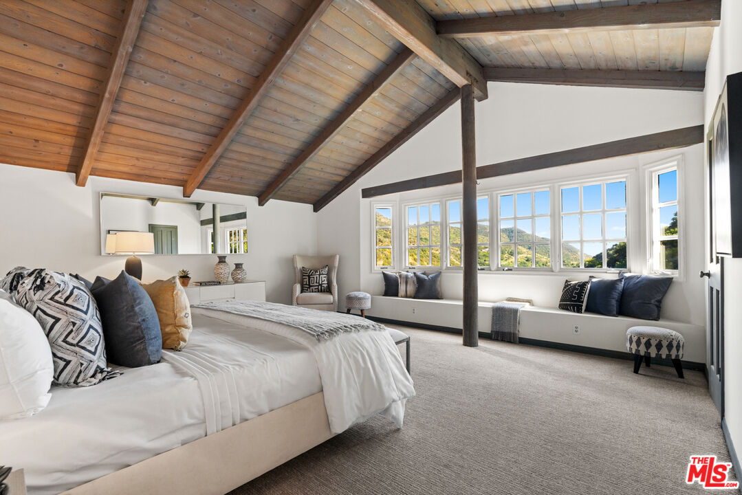 3371 Mandeville Canyon Road Los Angeles, CA 90049 - Photo 24 of 44 a bedroom with furniture and large windows