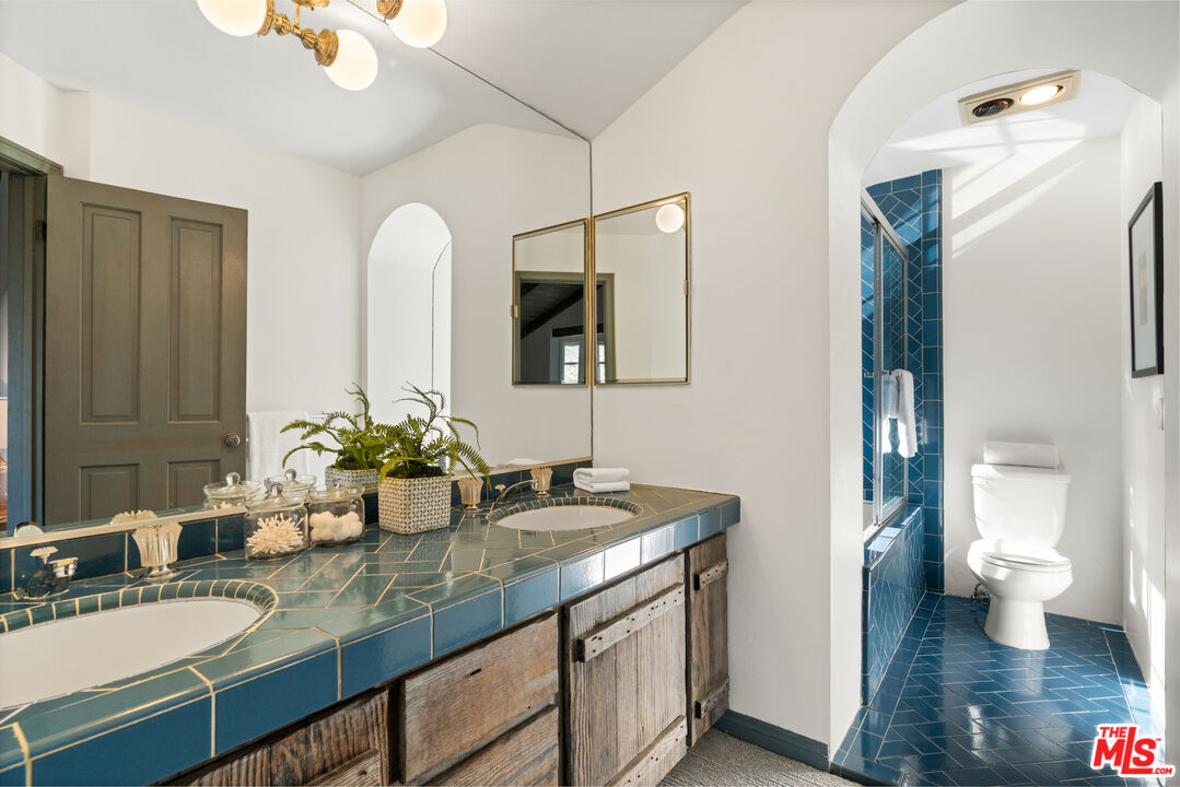 3371 Mandeville Canyon Road Los Angeles, CA 90049 - Photo 27 of 44 a bathroom with a granite countertop sink a large mirror and a toilet
