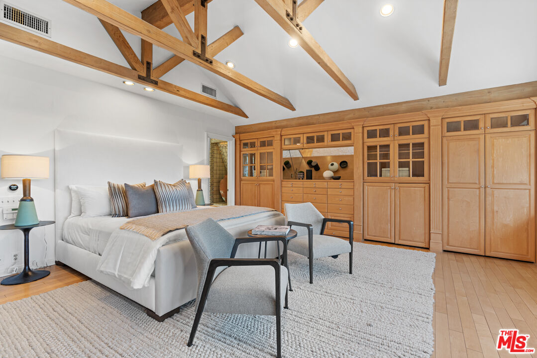 3371 Mandeville Canyon Road Los Angeles, CA 90049 - Photo 33 of 44 a spacious bedroom with a bed a table and chair