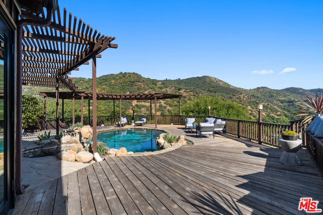 3371 Mandeville Canyon Road Los Angeles, CA 90049 - Photo 37 of 44 a view of a balcony with mountain view and wooden floor