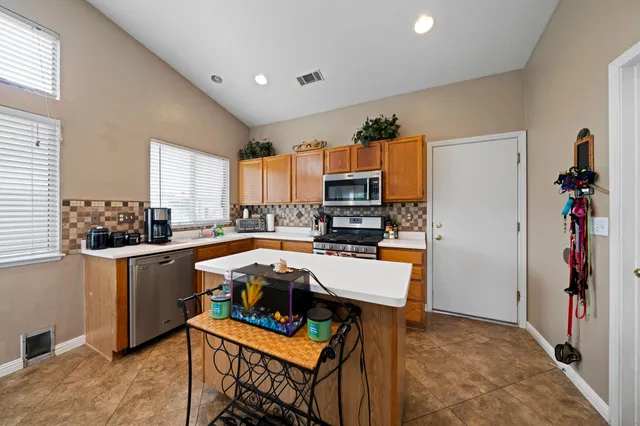 a kitchen with stainless steel appliances a sink a stove a refrigerator cabinets and living room view