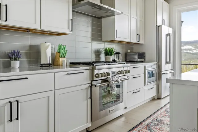 a kitchen with stainless steel appliances granite countertop white cabinets a stove a sink and dishwasher