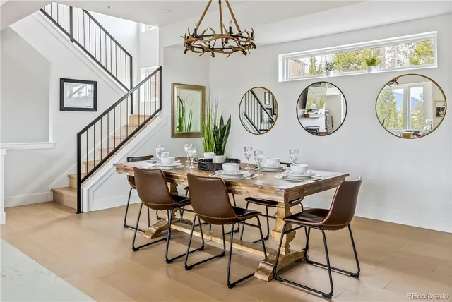 a dining room with wooden floor a chandelier a wooden table and chairs