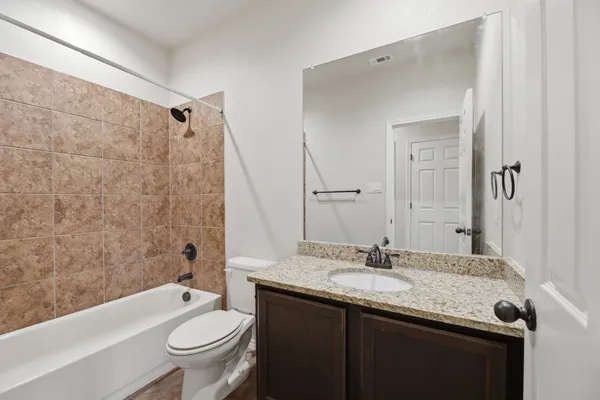 a bathroom with a granite countertop sink toilet a mirror and bathtub