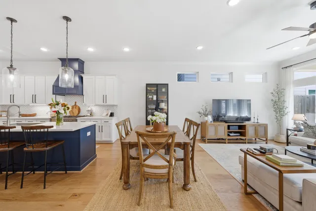 a kitchen with stainless steel appliances granite countertop a stove a sink a microwave a dining table and chairs with wooden floor